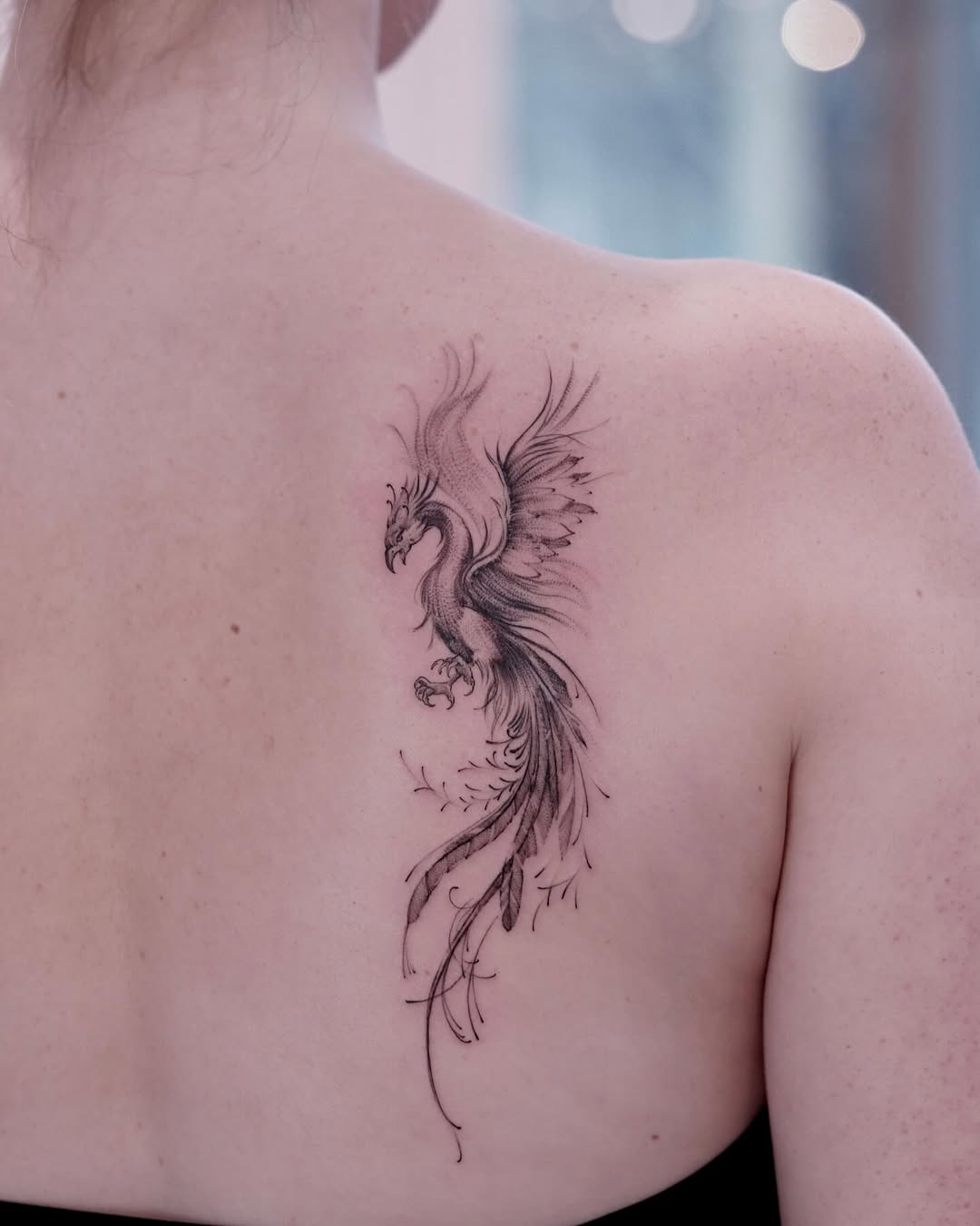 Elegant phoenix tattoo soaring on the back. Tattoo on skin