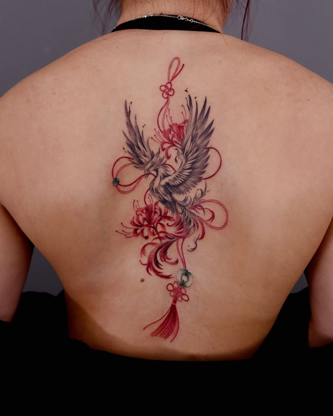 Elegant phoenix tattoo surrounded by floral motifs. Tattoo on skin