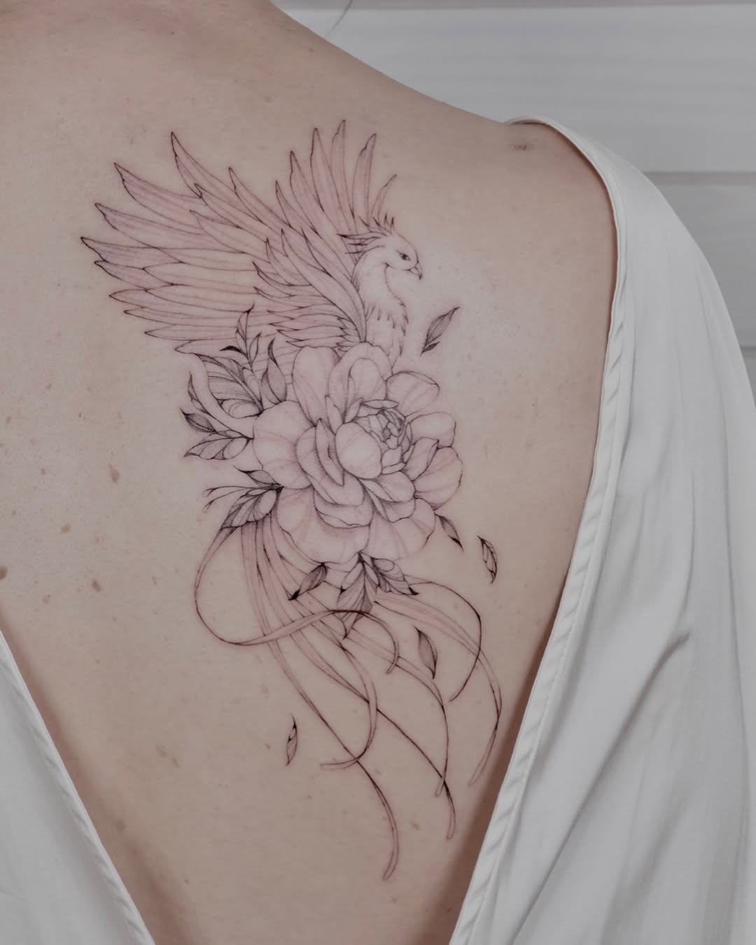 Elegant phoenix tattoo with floral details Tattoo on skin