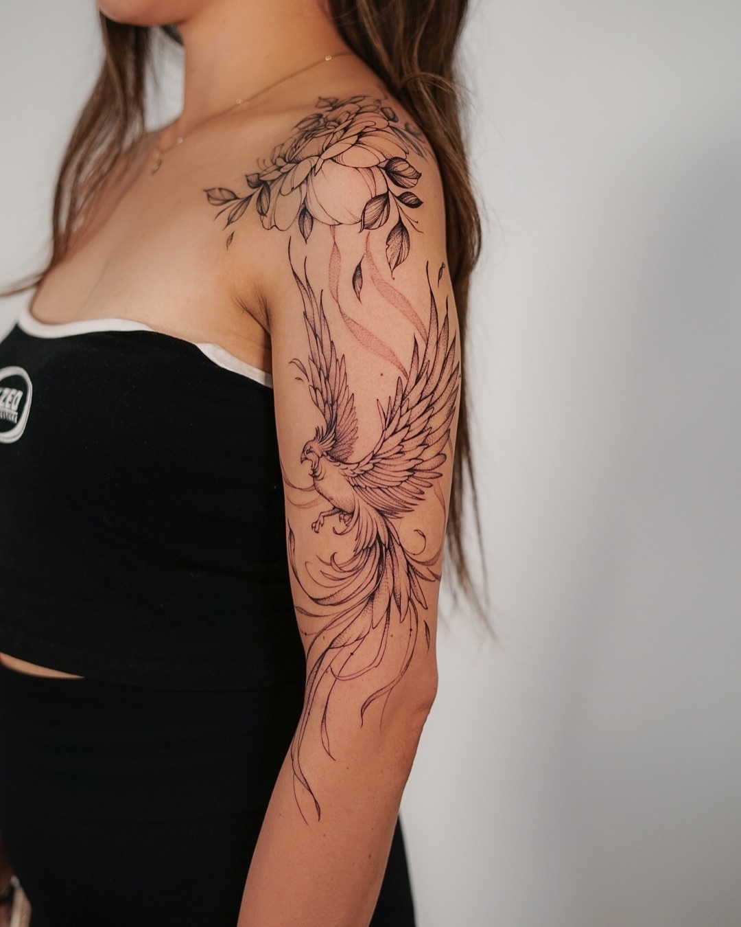 Elegant phoenix tattoo with floral embellishments Tattoo on skin