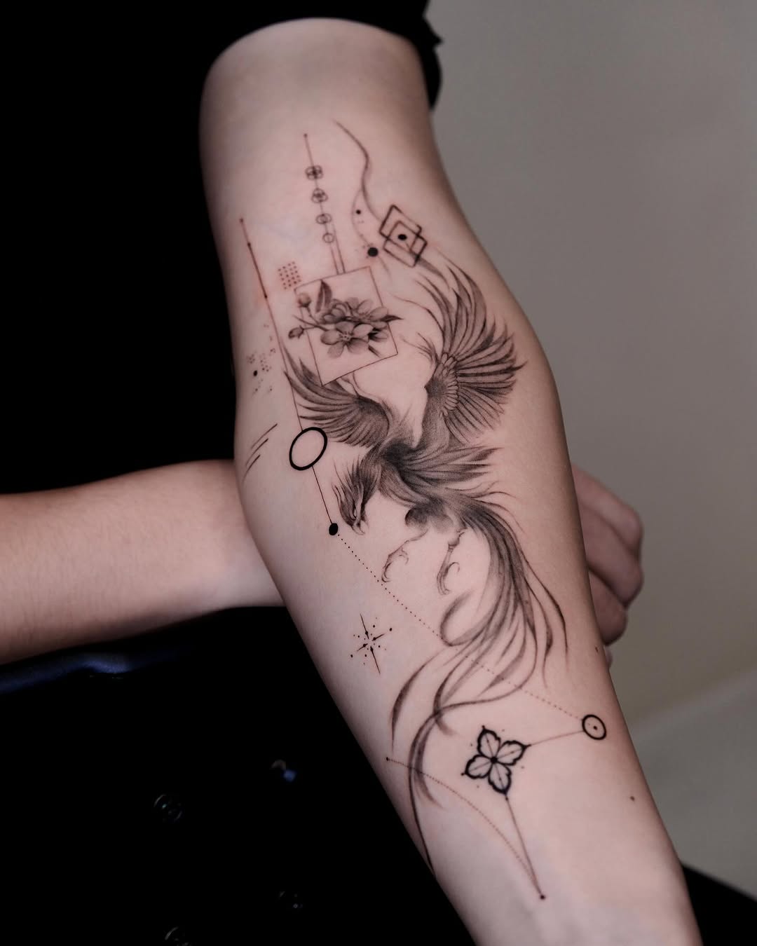 Elegant phoenix with floral accents and geometric details Tattoo on skin