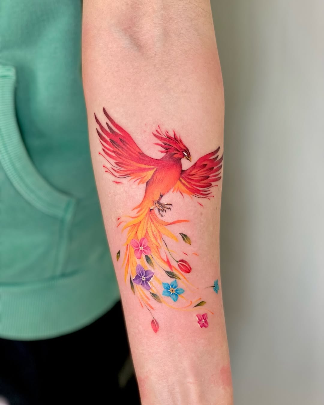 Stunning phoenix tattoo with vibrant floral accents Tattoo on skin