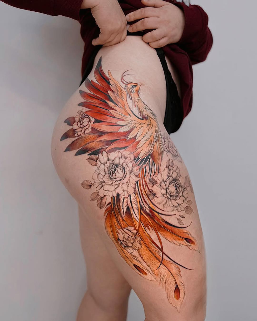 Stunning thigh phoenix tattoo with floral elements Tattoo on skin