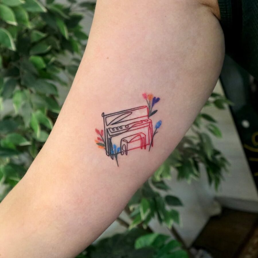 A vibrant piano tattoo surrounded by flowers Tattoo on skin