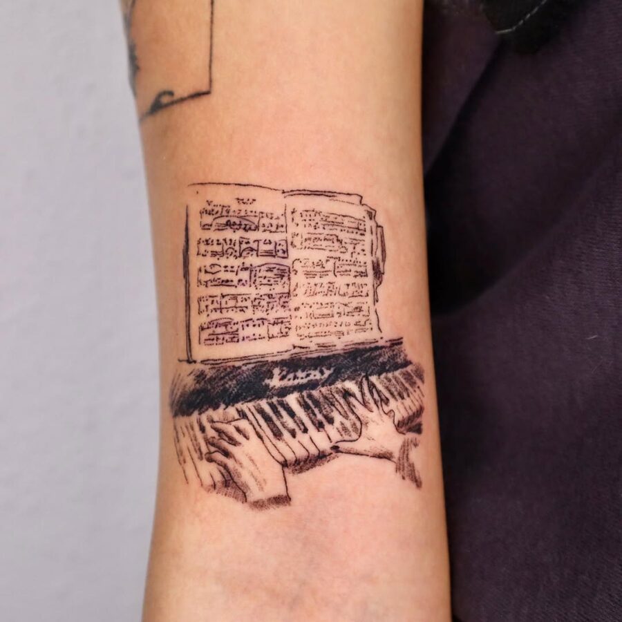 Detailed piano tattoo with sheet music illustration Tattoo on skin