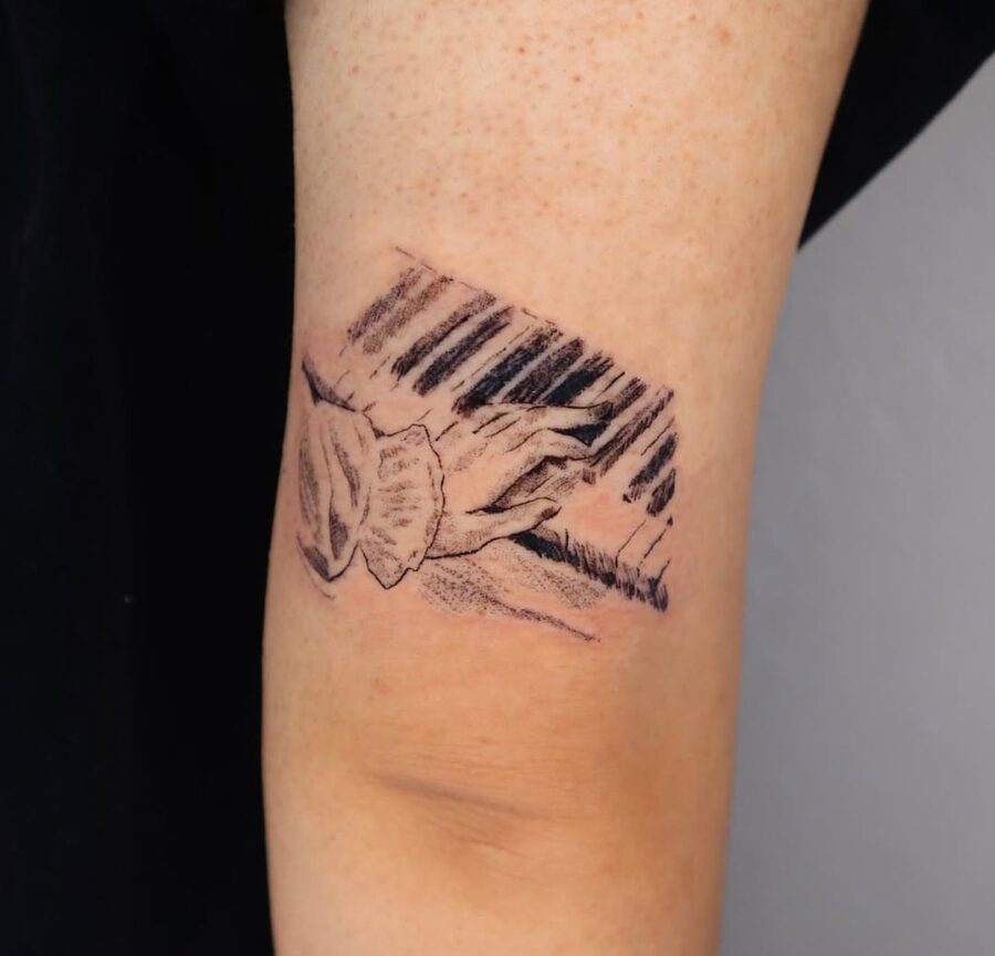 Intricate piano tattoo showcasing hands in harmony Tattoo on skin