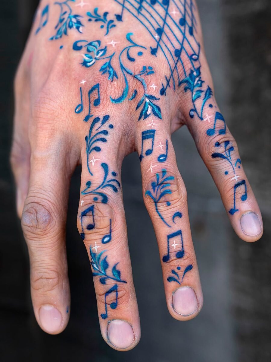Vibrant Musical Note Tattoos Adorning a Hand Tattoo on skin