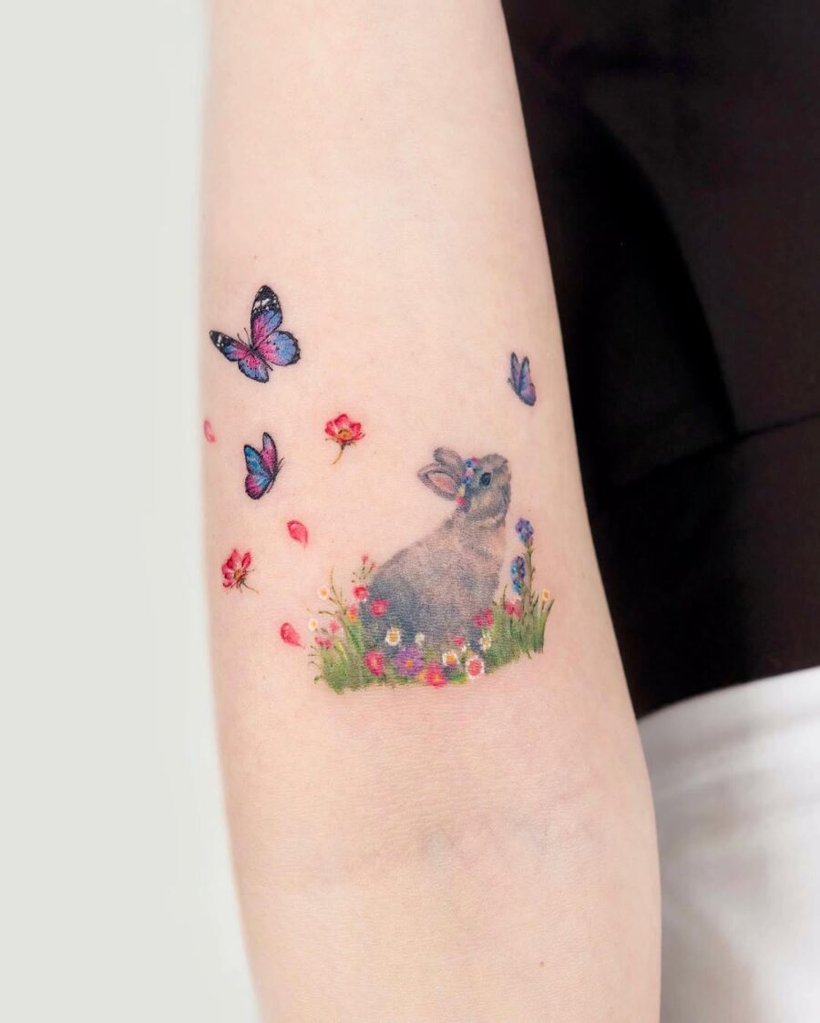 Charming rabbit tattoo surrounded by nature's beauty Tattoo on skin