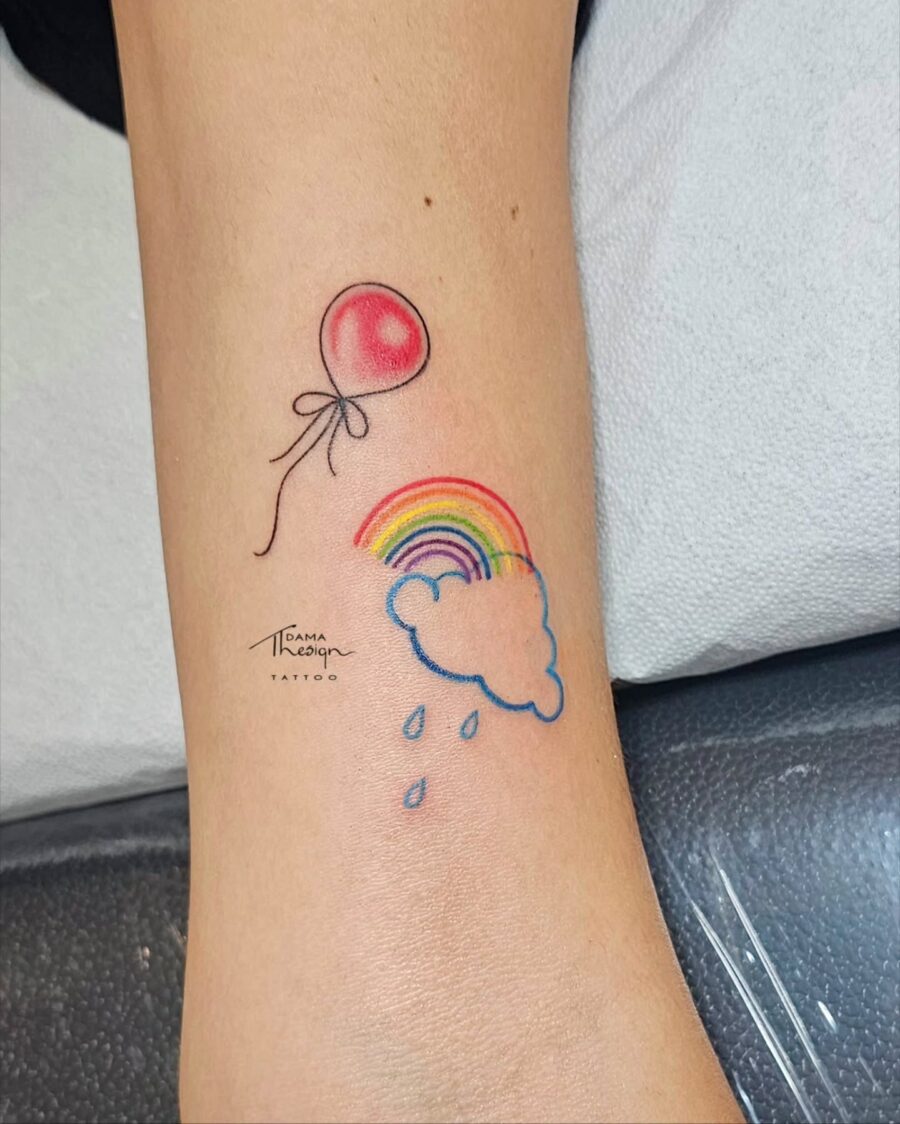 Whimsical rainbow baby tattoo with balloon Tattoo on skin