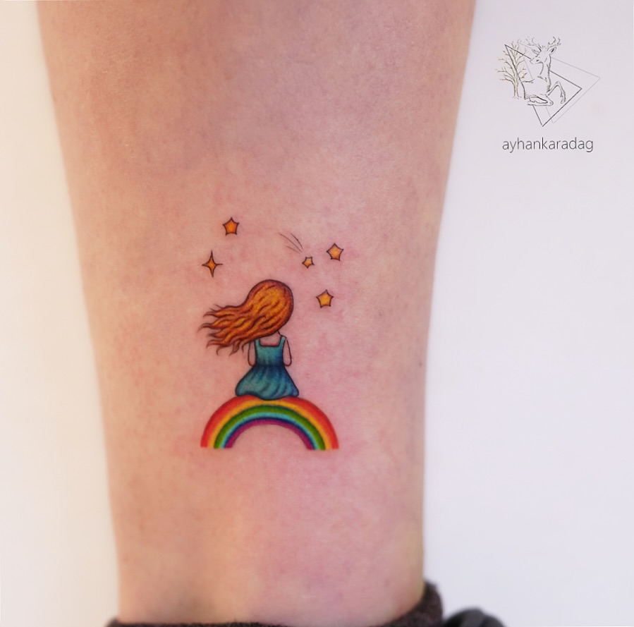 Whimsical rainbow baby tattoo with girl figure Tattoo on skin