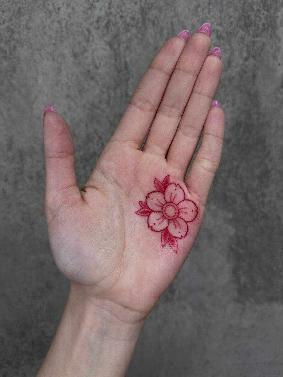 Delicate red ink flower tattoo on palm Tattoo on skin