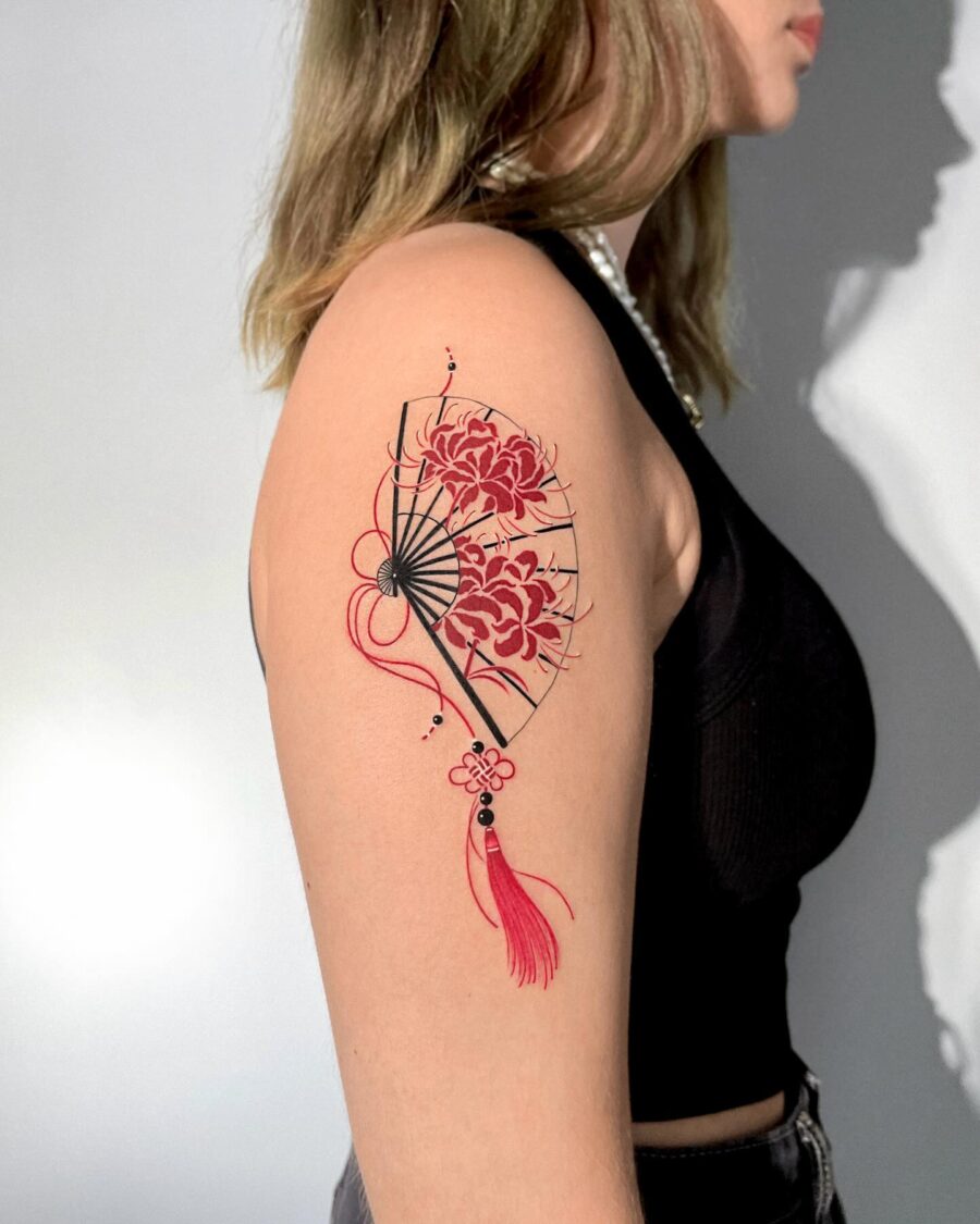 Elegant red ink fan tattoo with floral accents Tattoo on skin