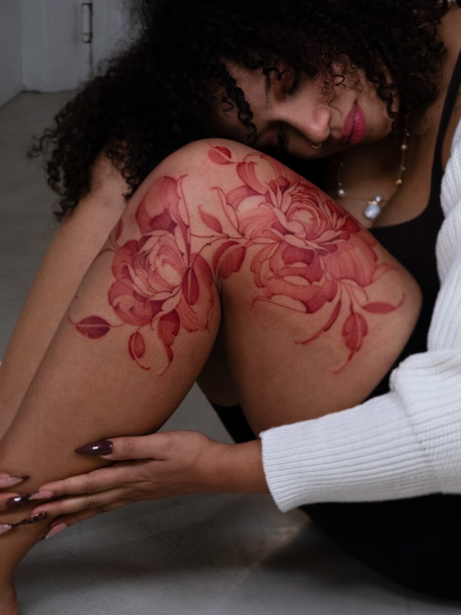 Elegant red ink roses on female thigh Tattoo on skin