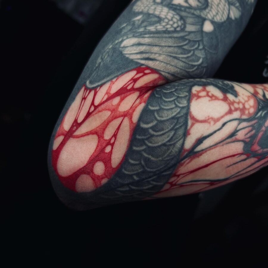 Intricate red ink tattoo design on arm Tattoo on skin