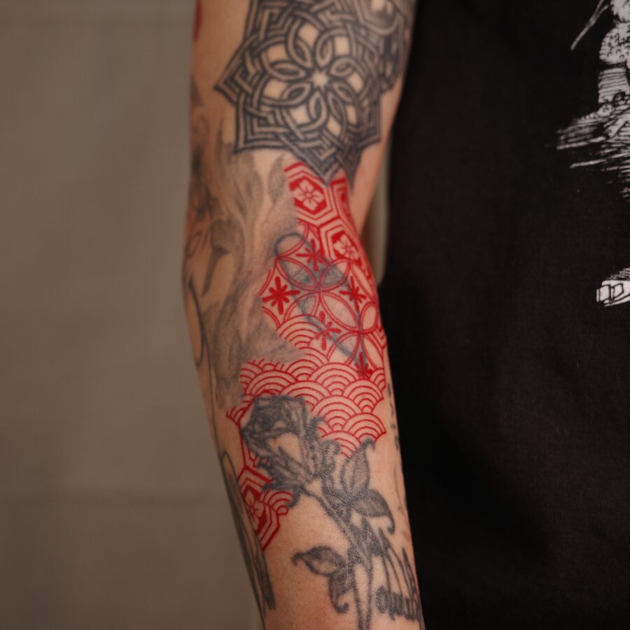 Striking red ink tattoo with floral elements Tattoo on skin