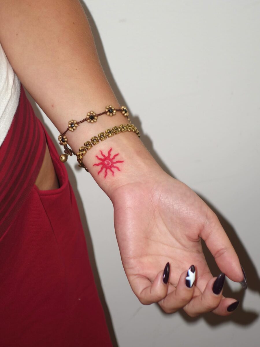 Vibrant red sun tattoo on wrist Tattoo on skin