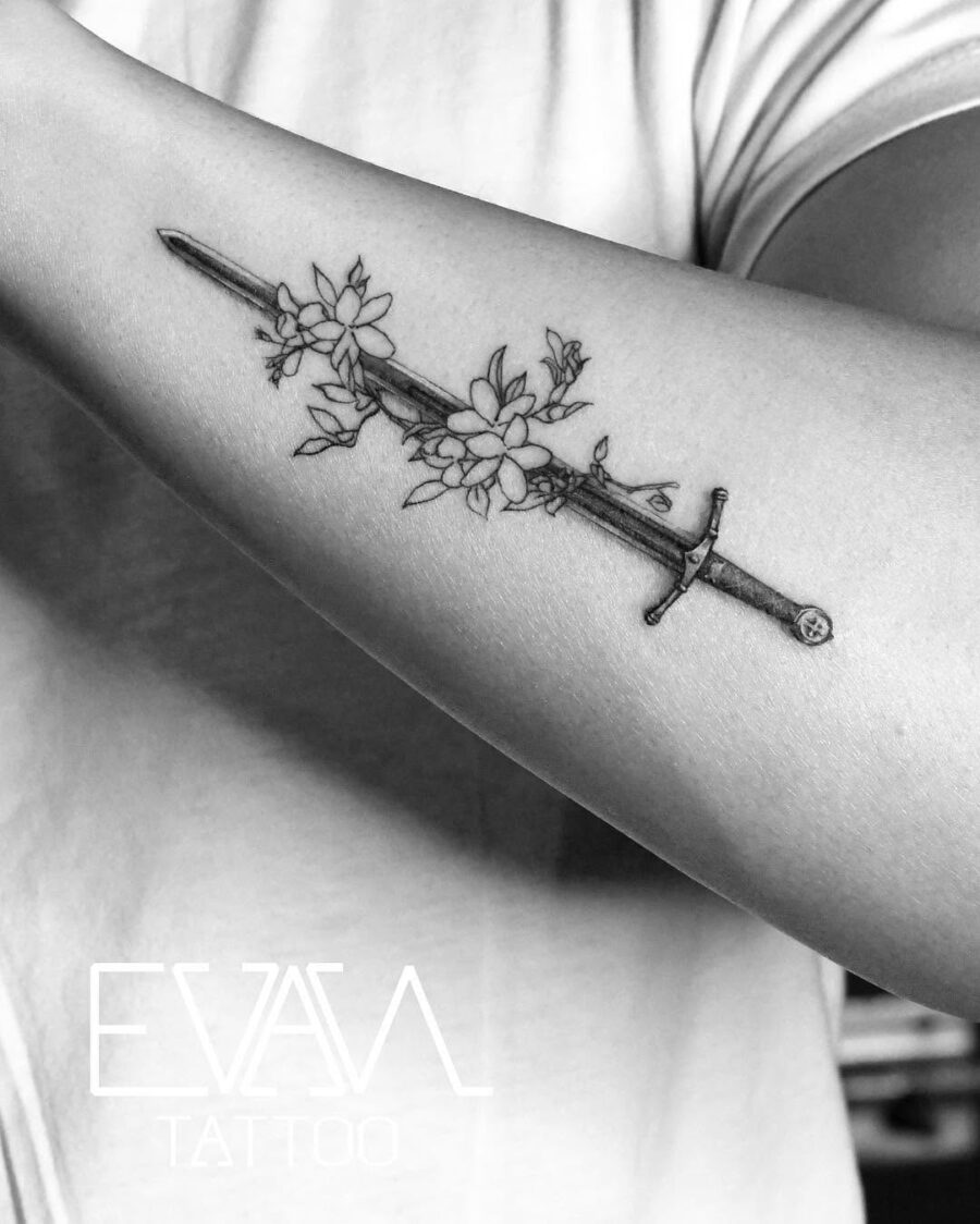 Elegant sword entwined with sampaguita flowers Tattoo on skin