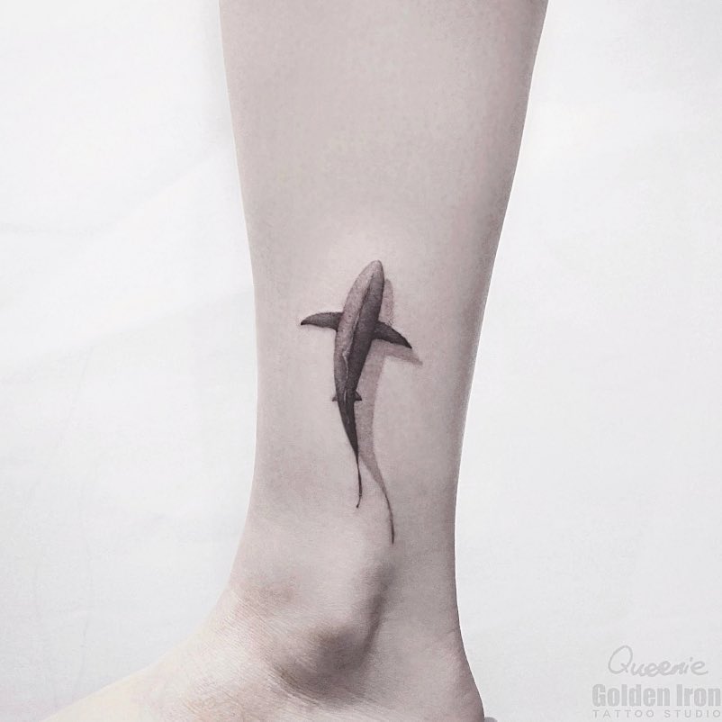 Minimalist shark tattoo on sleek leg Tattoo on skin
