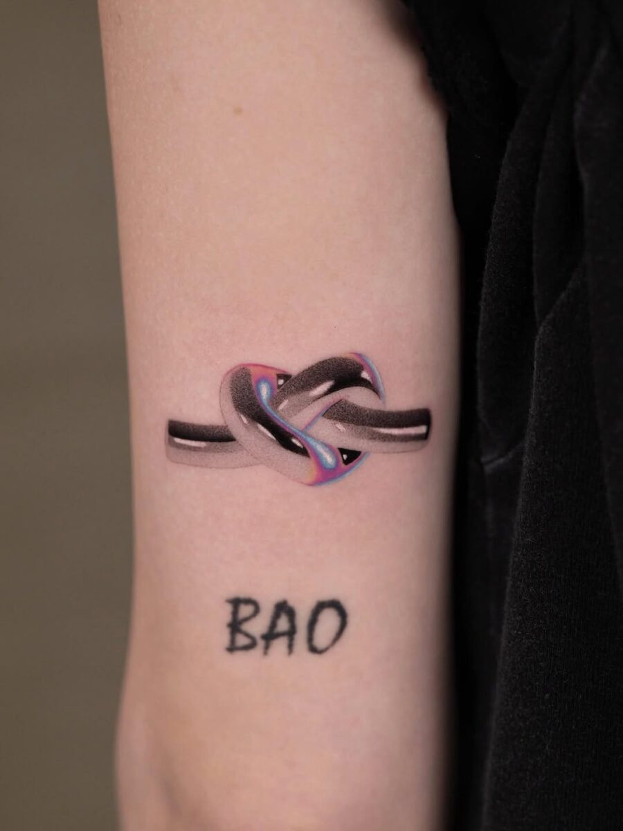 Intricate knotted design in silver ink. Tattoo on skin