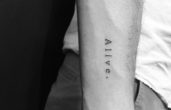 “Alive.” Simple Typewriter Text Tattoo Tattoo on skin