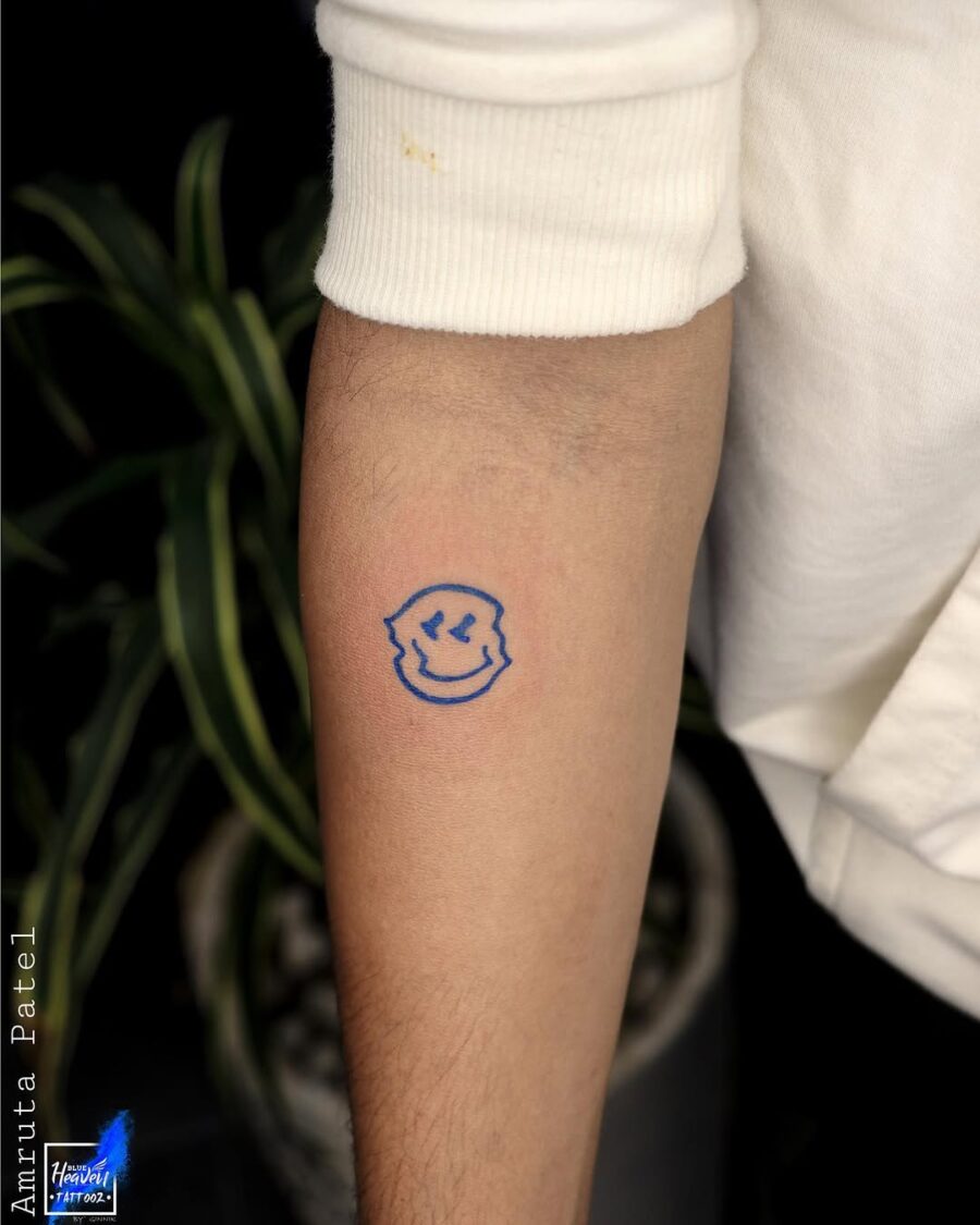 Charming blue smiley face tattoo on arm Tattoo on skin