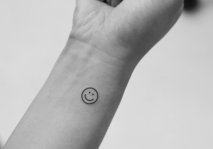 Charming minimalist smiley face tattoo on wrist Tattoo on skin