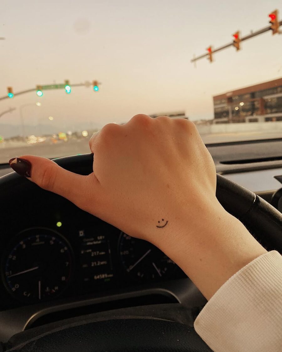 Charming smiley face tattoo on driving hand Tattoo on skin