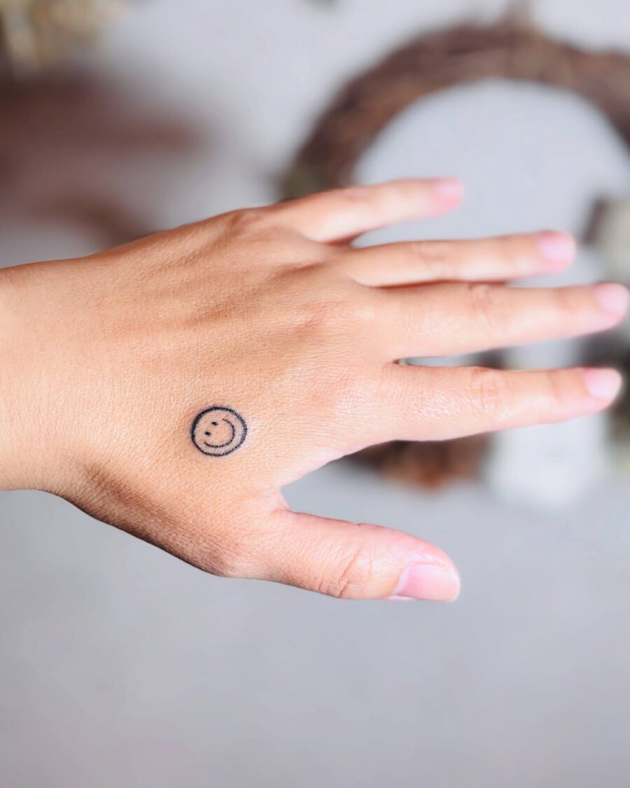 Charming smiley face tattoo on the hand Tattoo on skin