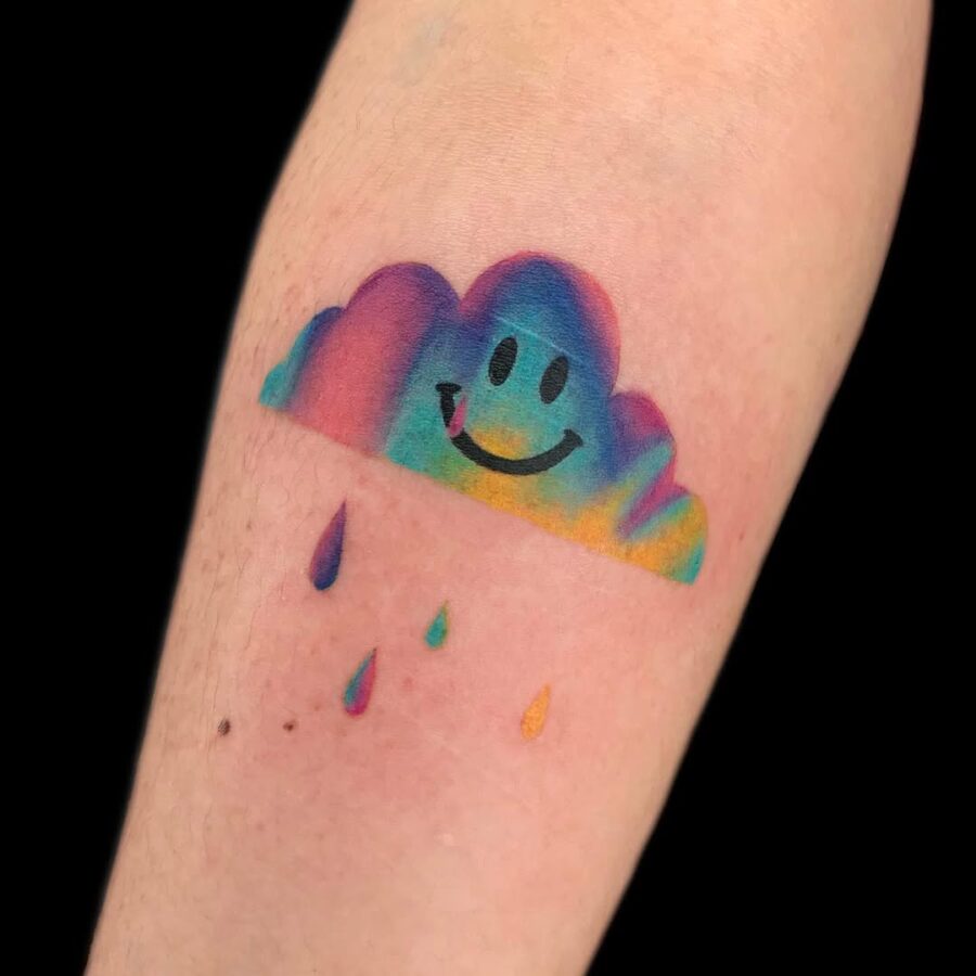 Joyful smiley cloud tattoo with rainbow hues Tattoo on skin