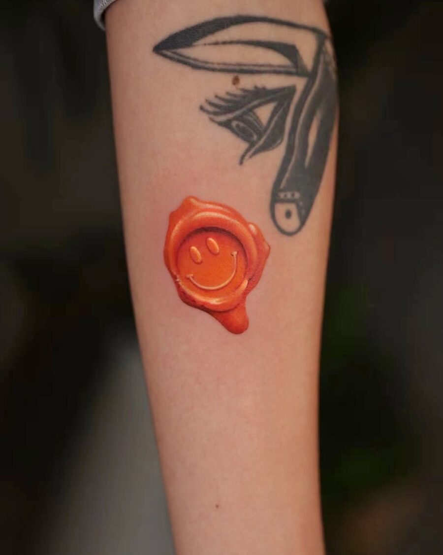 Vibrant Orange Smiley Face Tattoo on Arm Tattoo on skin