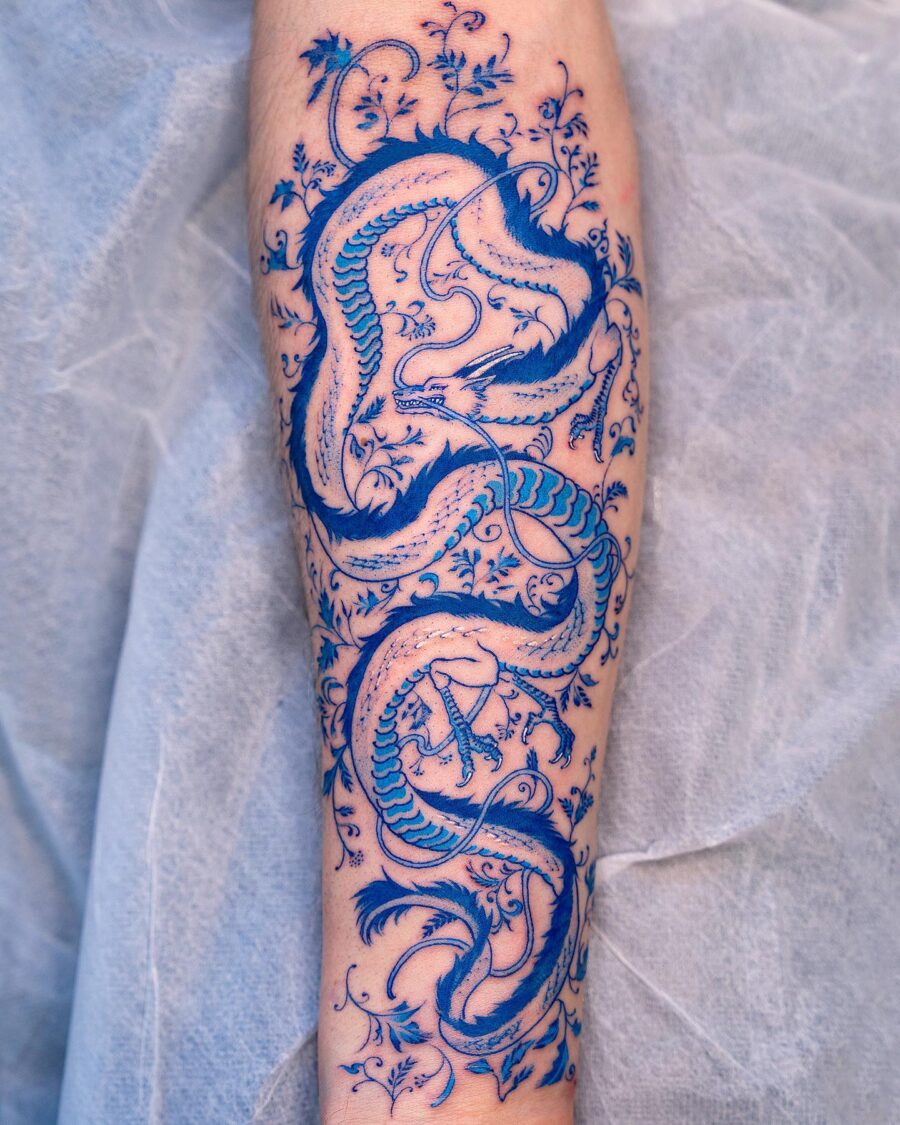 Intricate blue dragon tattoo with floral details Tattoo on skin