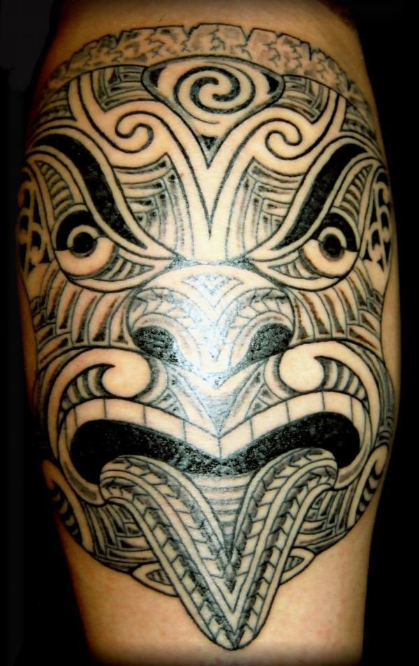 A Tribal Tattoo depicting a carved face Tattoo on skin