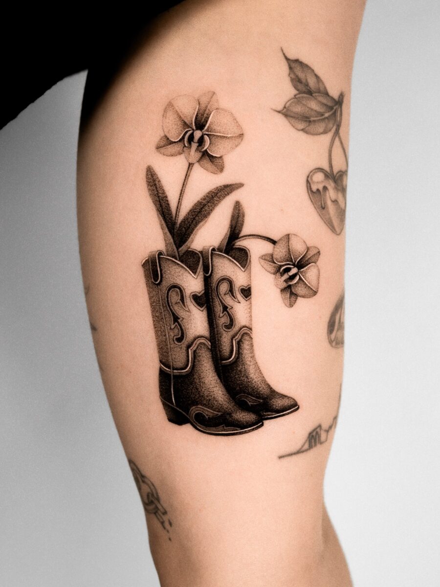 Stylish western boots with beautiful orchids Tattoo on skin