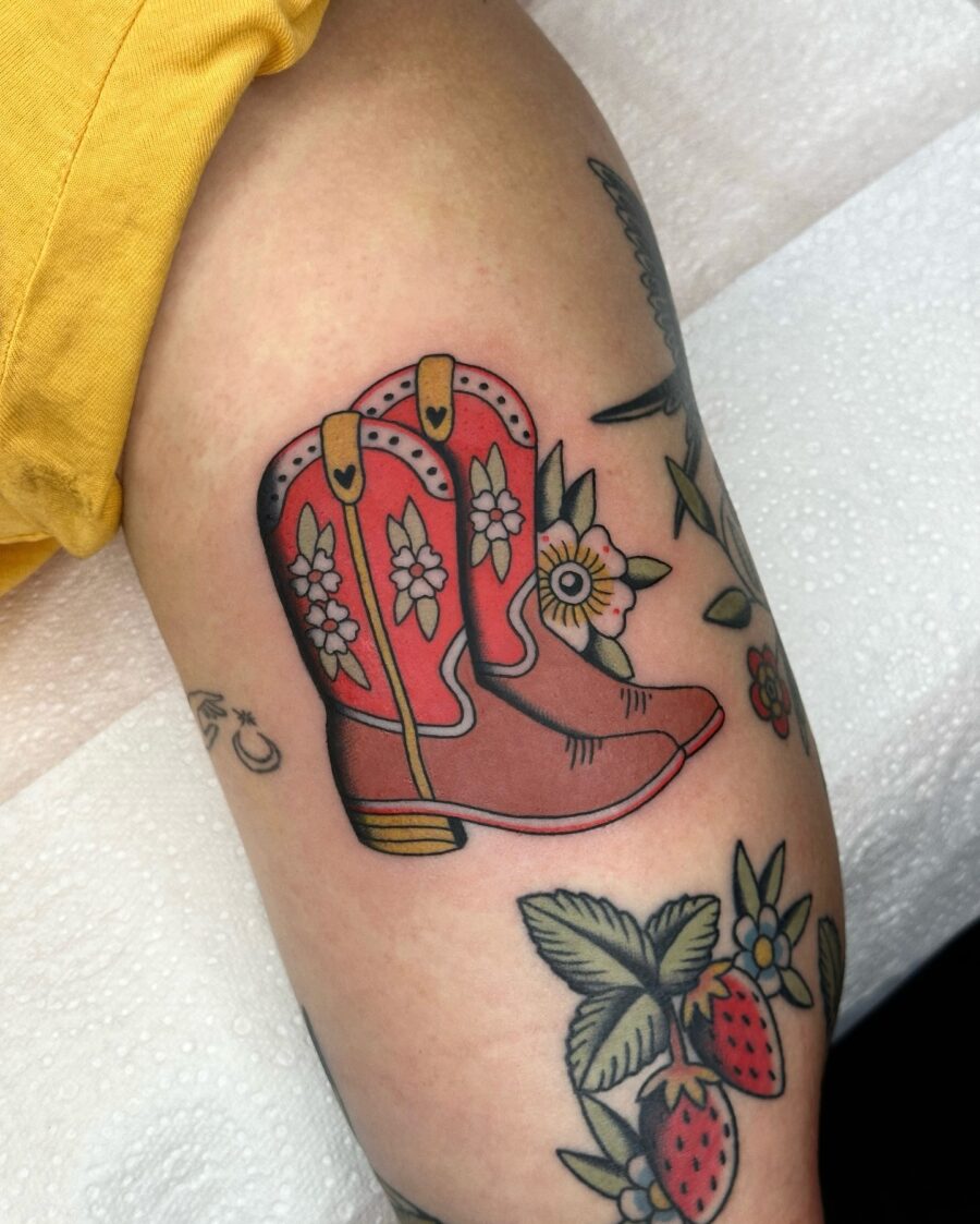 Vibrant cowboy boots tattoo with floral accents Tattoo on skin