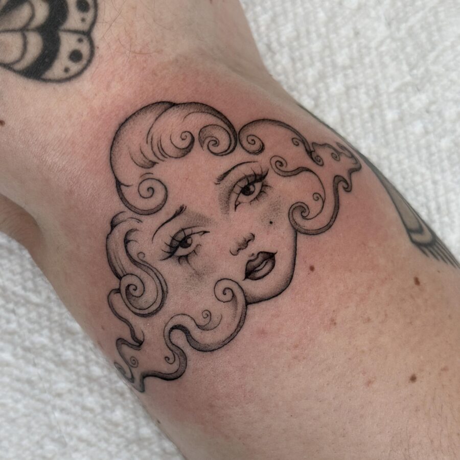 Charming whimsical face tattoo with curly hair Tattoo on skin