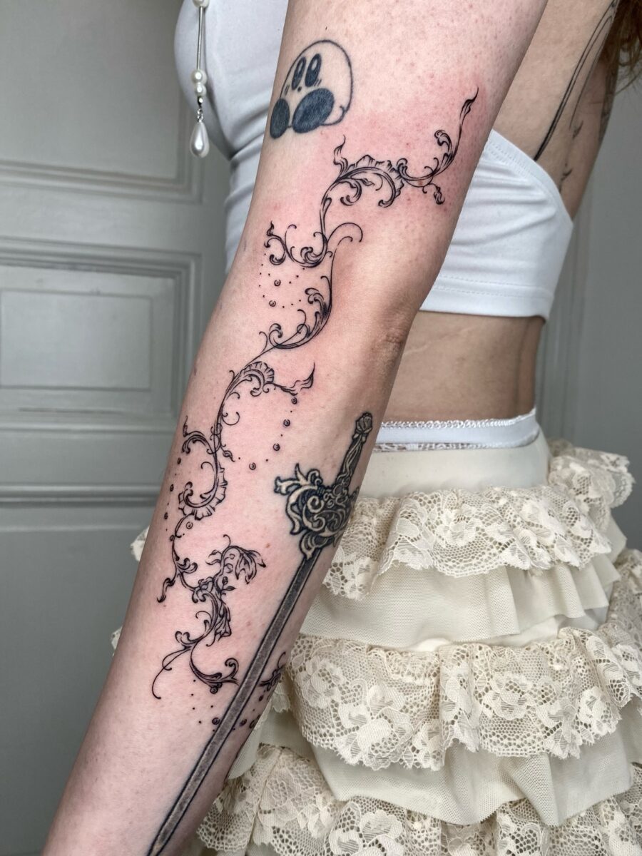 Intricate floral designs paired with a sword Tattoo on skin
