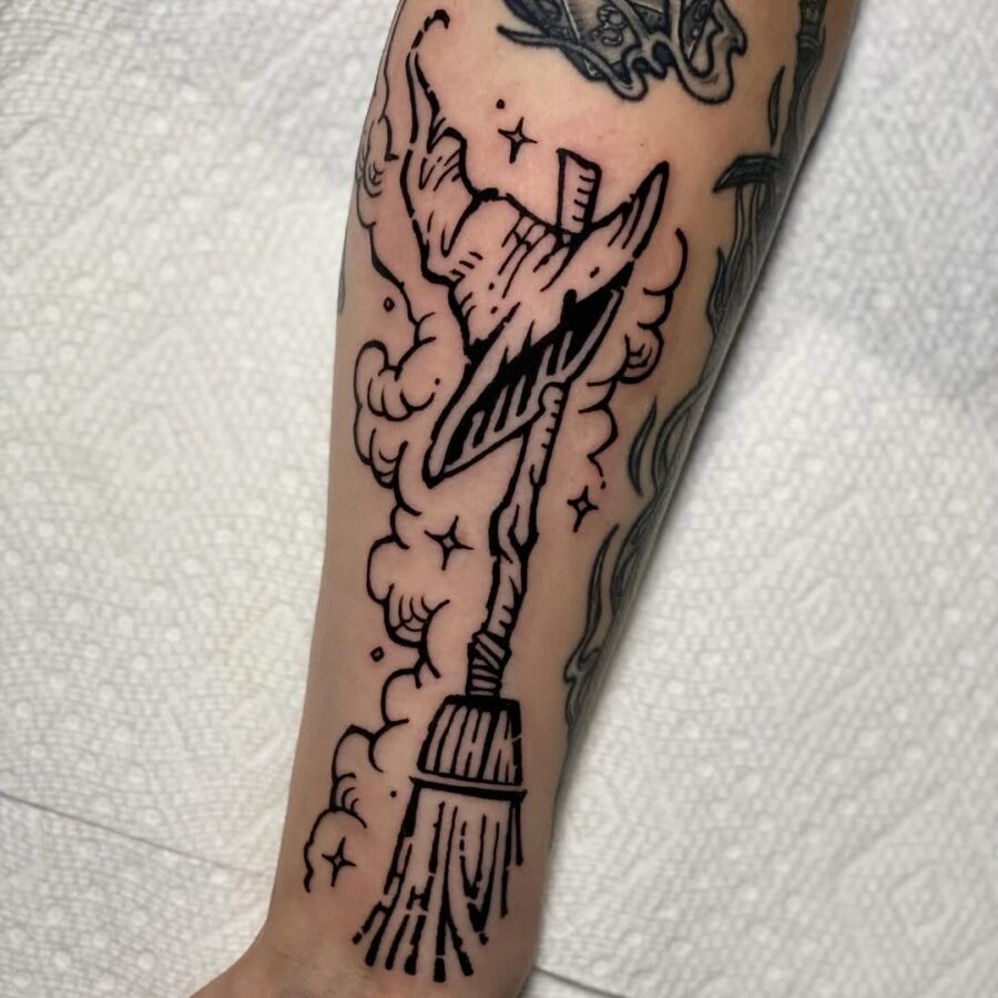 Magical witch hat with broomstick design Tattoo on skin