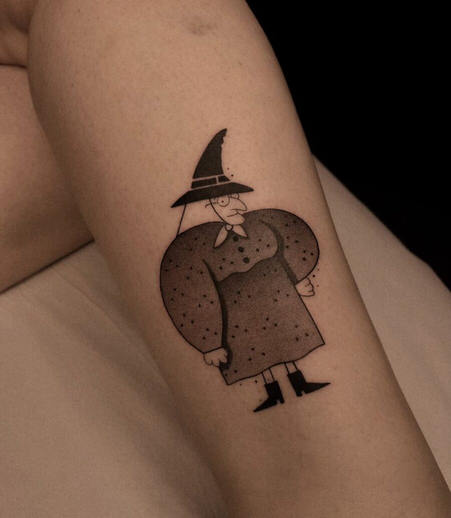Playful cartoon witch hat tattoo on arm Tattoo on skin